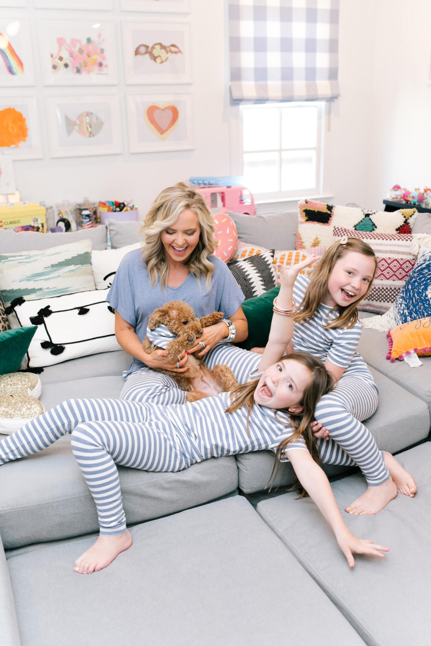 Mommy and Me Pajamas by popular Nashville fashion blog, Hello Happiness: image of a mom and her daughter sitting on a sectional couch with their goldendoodle puppy and wearing blue and white stripe Soma Intimates mommy and me pajamas. 