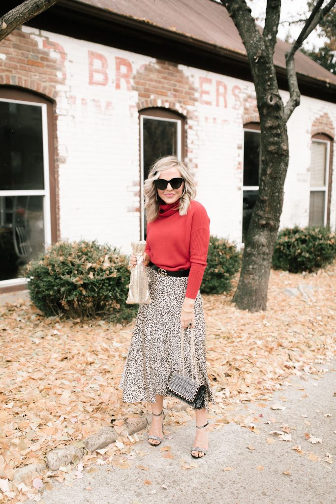 Cheers to Chicos RED by popular Nashville fashion blog, Hello Happiness: image of a woman outside wearing a Chicos red CASHMERE TURTLENECK, Chicos LEOPARD-PRINT MAXI SKIRT, Chicos SIMULATED STONE RING, and carrying a Chicos CONVERTIBLE TWEED SHOULDER BAG.