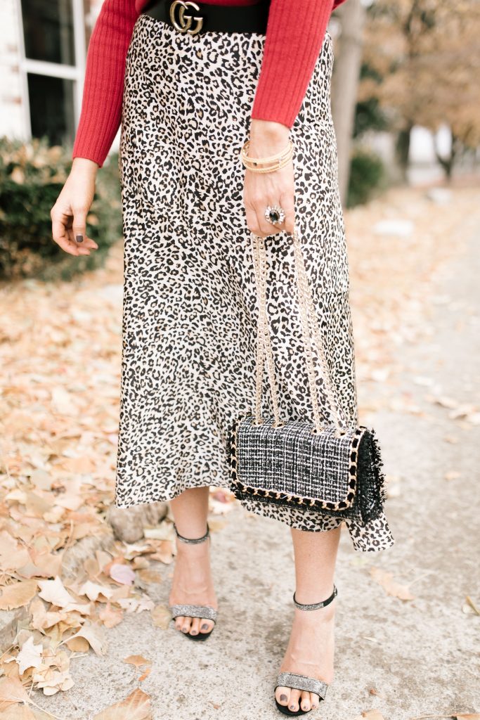 Cheers to Chicos RED by popular Nashville fashion blog, Hello Happiness: image of a woman outside wearing a Chicos red CASHMERE TURTLENECK, Chicos LEOPARD-PRINT MAXI SKIRT, Chicos SIMULATED STONE RING, and carrying a Chicos CONVERTIBLE TWEED SHOULDER BAG.