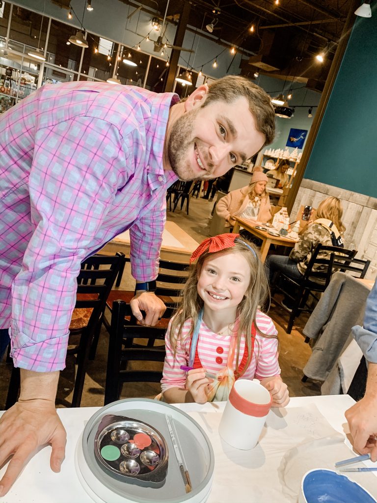 All Our Favorite Family Holiday Traditions by popular life and style blog, Hello Happiness: image of a father and daughter painting a ceramic mug. 