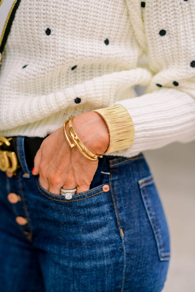 Accessory Concierge by popular Nashville fashion blog, Hello Happiness: image of Natasha Stoneking wearing a polka dot sweater and using a Accessory Concierge black, white, and gold purse strap and wearing a Accessory Concierge Nailed it bracelet, pyramid bracelet, Wire wrapped cuff bracelet, and deco gem drop earrings. 
