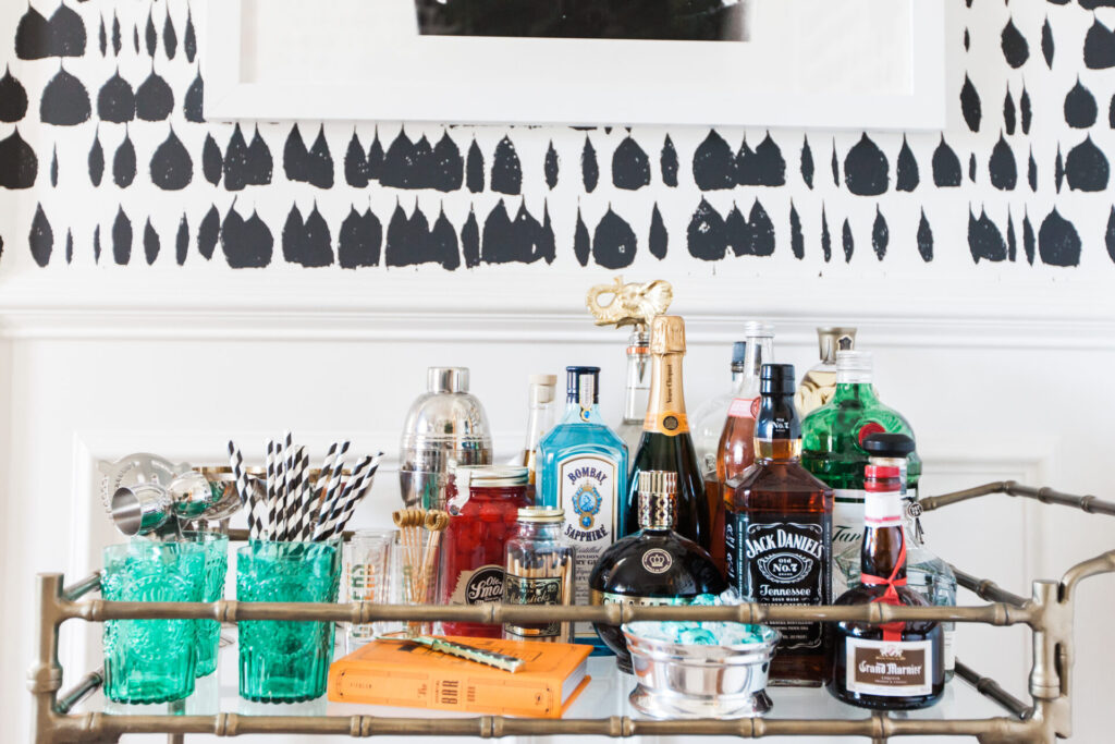 Bar Cart Essentials by popular Nashville lifestyle blog, Hello Happiness: image of a Ballard Designs Jill Bar Cart, framed Minted Moorten Cactus Study 1 print, Pottery Barn Harrison Bottle Coaster, Amazon The Essential Bar Book: An A-to-Z Guide to Spirits, Cocktails, and Wine, with 115 Recipes for the World's Great Drinks, and Schumacher QUEEN OF SPAIN wallpaper.