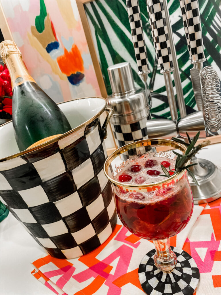 Cranberry Mimosa by popular Nashville lifestyle blog, Hello Happiness: image of a Mackenzie-Childs Courtly Check Enamel Wine Cooler, Bar Tool Set, Cocktail Shaker, and Wine Glass.